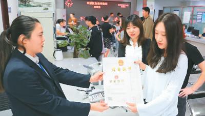 河北省承德市網(wǎng)絡(luò)代購經(jīng)營者陳晨(右)從工作人員手中接過帶有統(tǒng)一社會(huì)信用代碼的營業(yè)執(zhí)照。 劉環(huán)宇攝(人民圖片)