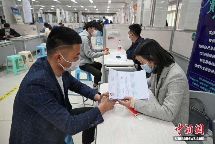 4月14日，招聘者在查看求職者簡(jiǎn)歷。<a target='_blank'  data-cke-saved- >中新社</a>記者 王剛 攝